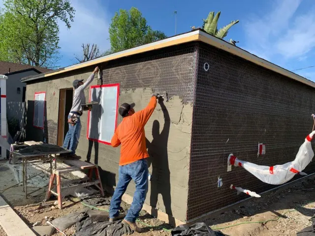 Crew applying stucco to the walls of a new backyard ADU