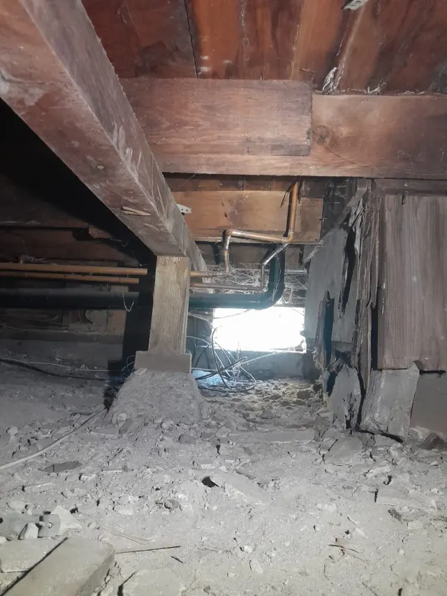 Foundation and repair in Los Angeles: the crawl space under a raised wood floor, with pipes along the joists