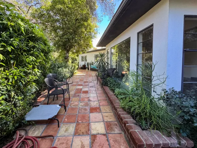 Full remodel in Los Angeles: tall black-framed windows along the tiled side patio