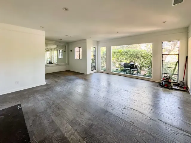 Full remodel in Los Angeles: new wood-look plank flooring across a living room with tall windows