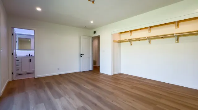 Full remodel in Thousand Oaks: bedroom with an air register above the door, recessed lights and a new bathroom beyond