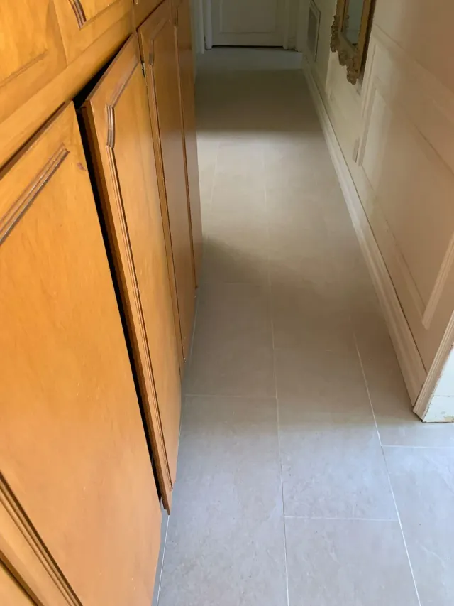 Light floor tile laid along wood cabinets in a Claremont kitchen remodel