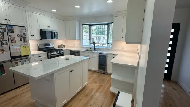 Remodeled Torrance kitchen with white shaker cabinets, a marble-look island, recessed lights and wood floors