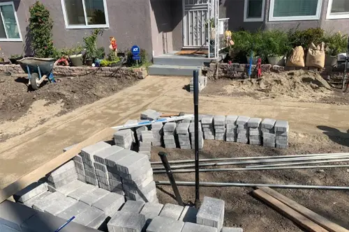 Front yard under construction with concrete blocks stacked for a new wall