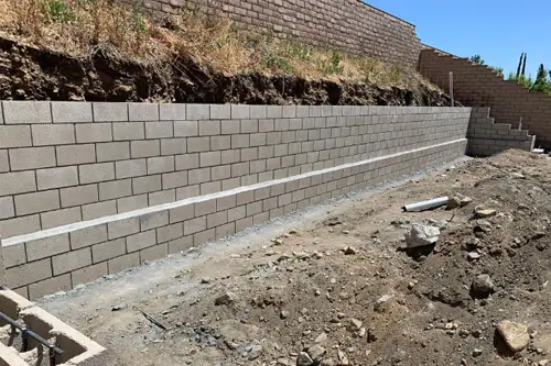 New concrete block retaining wall along a dirt slope