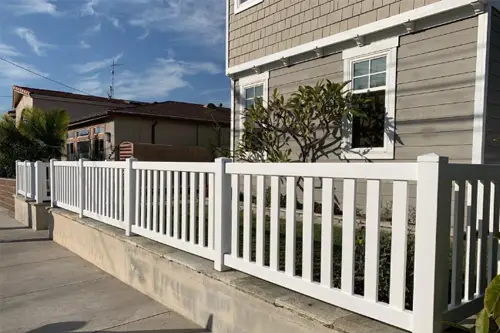 White picket fence on a low wall in front of a house